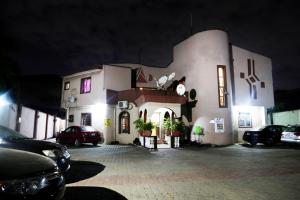 un grand bâtiment blanc avec des voitures garées dans un parking dans l'établissement CLASS COTTAGE, à Ikeja