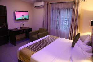 une chambre d'hôtel avec un lit, une chaise et une télévision dans l'établissement CLASS COTTAGE, à Ikeja