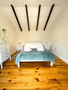 a bedroom with a bed and a wooden floor at Holmdale Holiday Cottages in Rye