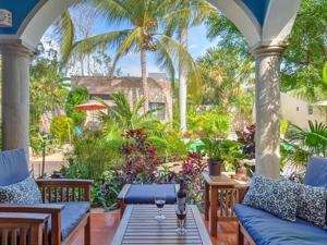 un porche con sofás azules, una mesa y palmeras en Casa 411 en Mérida