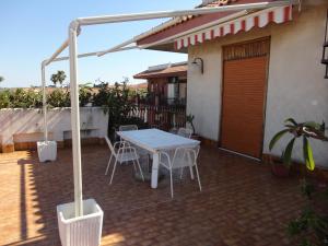 een patio met een tafel en stoelen op een huis bij Casa delle Pomelie - Taormina & Etna Panoramic Views in Riposto