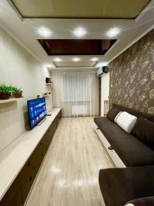 a living room with a couch and a tv in it at Роскошные апартаменты в центре in Temirtaū