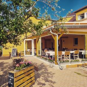 un edificio giallo con patio arredato con tavoli e sedie di Gasthaus Zur Hecke a Schönefeld