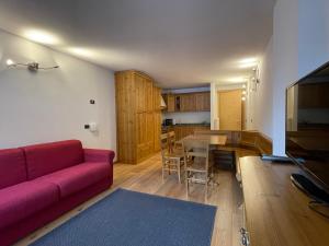 ein Wohnzimmer mit einem roten Sofa und einem Tisch in der Unterkunft Residence Regina delle Alpi in Santa Caterina Valfurva