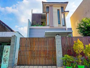 a house with a wooden gate and a fence at SPOT ON 91530 Sumpil Syariah in Malang