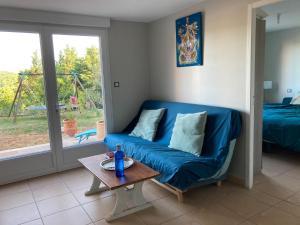 salon z niebieską kanapą i stołem w obiekcie Logement indépendant avec jardin à Rodez Aveyron w mieście Onet le Château
