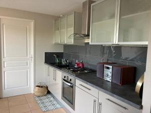 a kitchen with white cabinets and a microwave at Logement indépendant avec jardin à Rodez Aveyron in Onet le Château