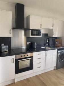 a kitchen with white cabinets and a stove top oven at Ben Nevis Manor Lodge & Indoor Private Hot-Tub in Fort William