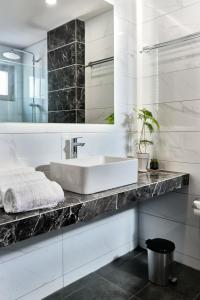 ein weißes Badezimmer mit einem Waschbecken und einem Spiegel in der Unterkunft Grapevines Hotel in Alikanas