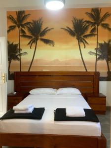 a bedroom with a large bed with palm trees on the wall at Hostal San Lázaro 1103 in Havana