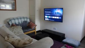 uma sala de estar com um sofá e uma televisão de ecrã plano em Sligo Wild Atlantic Cottage em Sligo