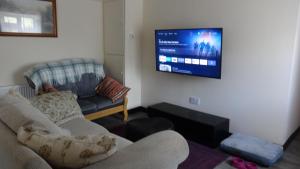 sala de estar con sofá y TV de pantalla plana en Sligo Wild Atlantic Cottage, en Sligo