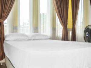- un lit avec deux oreillers dans une chambre dotée de fenêtres dans l'établissement SPOT ON 91463 Obby Guest House, à Balikpapan