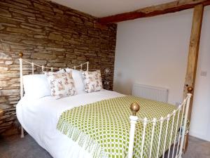 ein Schlafzimmer mit einem weißen Bett und einer Steinmauer in der Unterkunft Hay Barn, Penrheol Farm, Unique Barn Conversion in Builth Wells