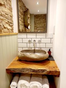 y baño con lavabo de piedra y espejo. en Hay Barn, Penrheol Farm, Unique Barn Conversion, en Builth Wells
