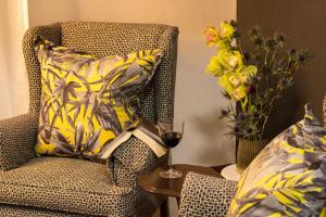 a chair with a glass of wine and a vase of flowers at 5 Rembrandt Guesthouse in Somerset West