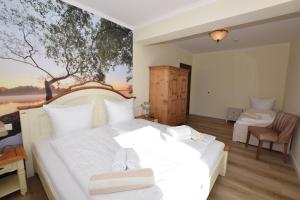 a bedroom with a white bed with a painting on the wall at Landhaus Hideaway mit Aussenpool, Sauna und Kamin in Bosau