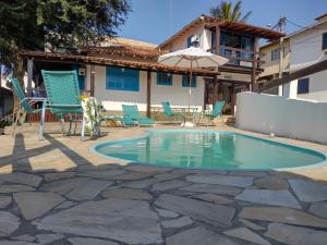a pool with chairs and a table and an umbrella at Mar de Maria Pousada in Búzios