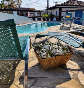 um cesto de plantas sentado ao lado de uma cadeira ao lado de uma piscina em Mar de Maria Pousada em Búzios