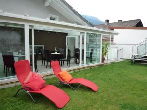 zwei rote Stühle und ein Tisch auf dem Rasen in der Unterkunft Appartementhaus Klammer in Sillian