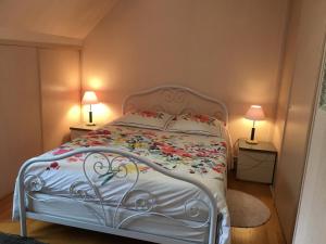 een slaapkamer met een wit bed met bloemen erop bij Chambres d'hotes Chez Annie in Brélès