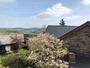 una casa con un árbol floreciente delante de ella en Hay Barn, Penrheol Farm, Unique Barn Conversion, en Builth Wells