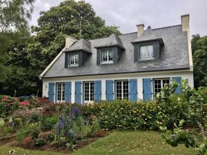 una vecchia casa con persiane blu in giardino di Chambres d'hotes Chez Annie a Brélès
