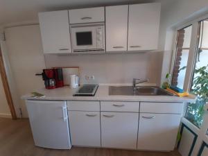 a kitchen with white cabinets and a sink and a microwave at Graunke Vier in Grube +8 photos