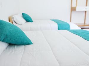 Una cama blanca con almohadas verdes. en hotel boutique lila&co en Tonatico
