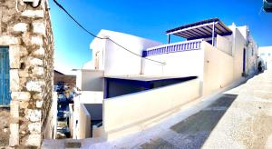 a white building with a balcony on a street at Astypalea Apartments in Astypalaia Town