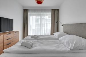 a large white bed with pillows and a television at Wave Apartments - Yacht Park 2 in Gdynia