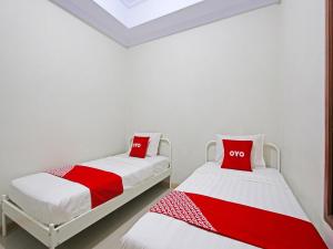 2 Betten in einem Zimmer mit roter und weißer Bettwäsche in der Unterkunft OYO 91487 Ib Homestay Syariah in Tegal