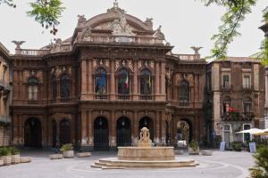 a large building with a fountain in front of it at San Berillo house in Catania