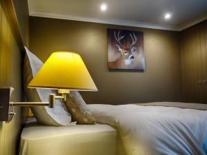 ガディンヌにあるB&B Aux 4 Saisonsのベッドルームのベッドの横にランプが備わります。