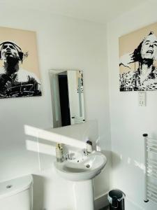 a white bathroom with a sink and a mirror at Funky cozy cottage with outside space in Eastbourne