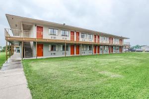 a large building with red doors and a grass field at Studio Suites in San Antonio