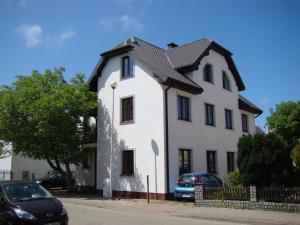 ein weißes Haus mit schwarzem Dach auf einer Straße in der Unterkunft Villa California in Darłówko