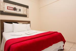 a bedroom with a red blanket on a bed at Gabvini Hotel in Lima Duarte