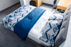 Una cama con una manta azul encima. en Empress House en Mánchester