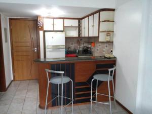 cocina con barra y 2 taburetes en Apartamento Barra Tropical Residence, en Salvador
