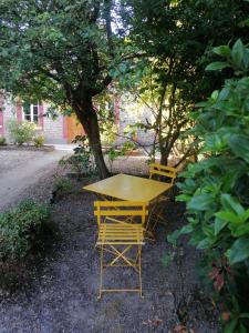 ein gelber Tisch und zwei Stühle unter einem Baum in der Unterkunft Chez Joséphine 