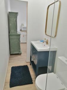 een badkamer met een wastafel, een toilet en een spiegel bij Chez Joséphine 