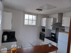 a kitchen with white cabinets and a wooden table at Maison Face au Mont avec extérieur in Avranches