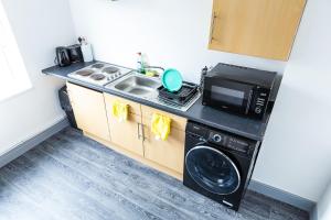 a kitchen with a sink and a washing machine at Empress House in Manchester