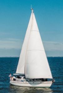 a sailboat with a white sail on the water at Adventures with friends & family stay only or learn to set sail with skipper Casey in Hoorn
