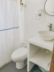 La salle de bains blanche est pourvue de toilettes et d'un lavabo. dans l'établissement Mamallena Beachside Rincon del Mar, à Rincón