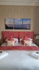 1 cama grande con cabecero rojo y 2 ventanas en Craignelder Hotel en Stranraer