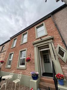 a brick house with two chairs and a door at Abbey House B & B in Penrith