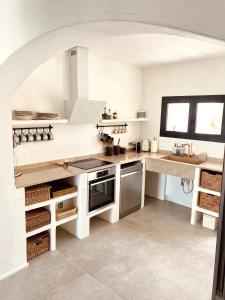a kitchen with white counters and an archway at Can Yuca II in Cala Mondrago