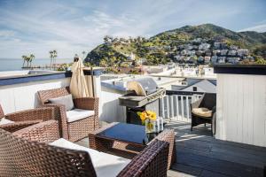 a balcony with wicker chairs and a table with a grill at Hermosa Hotel in Avalon
